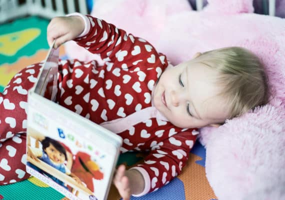 baby reading wearing a heart-covered onesie