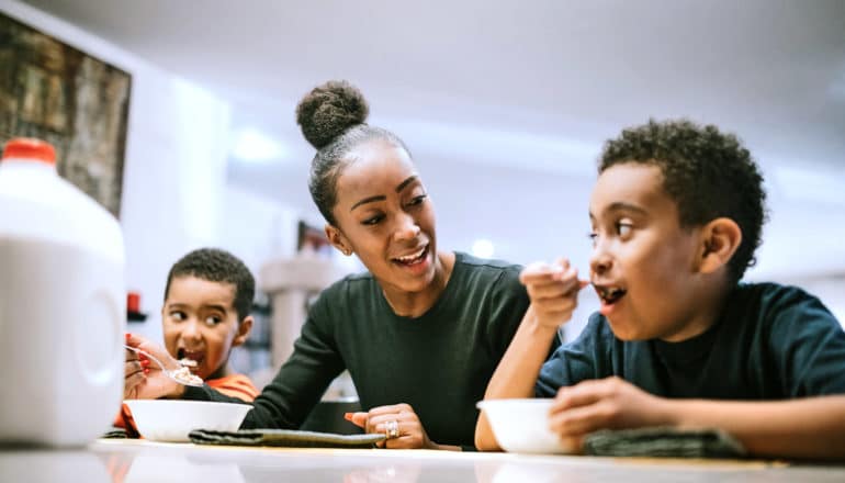 mom between two boys eating cereal