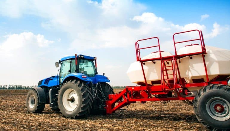 tractor in field pulls wagon with tanks of liquid