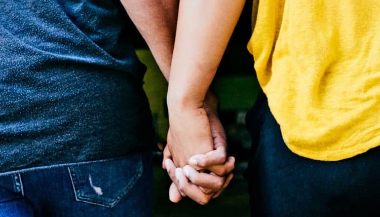 A couple holds hands as they walk through a doorway together.