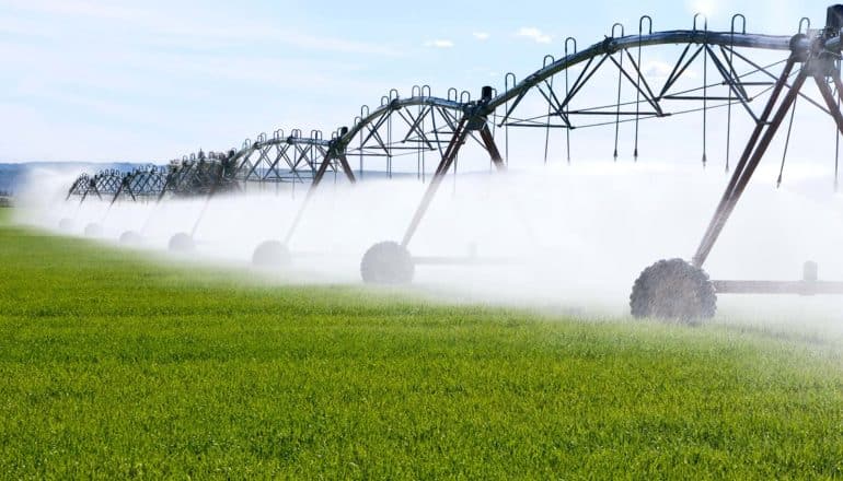 An irrigation system waters a green field.