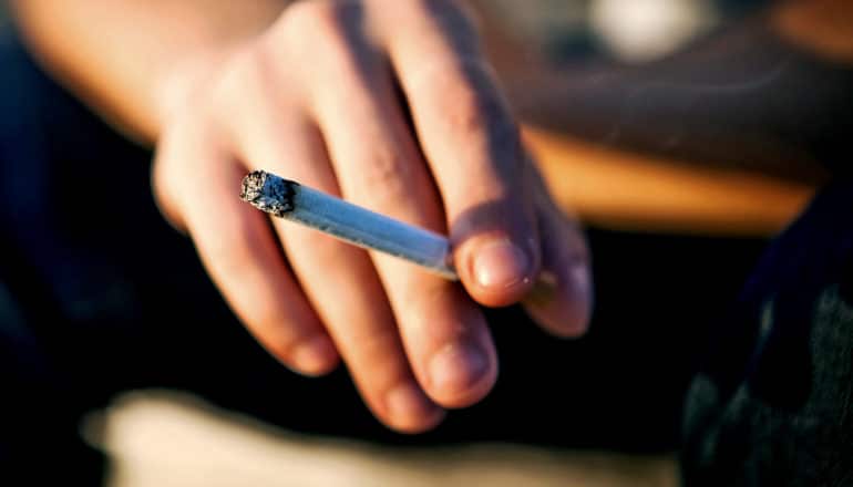A person holds a cigarette in their right hand.