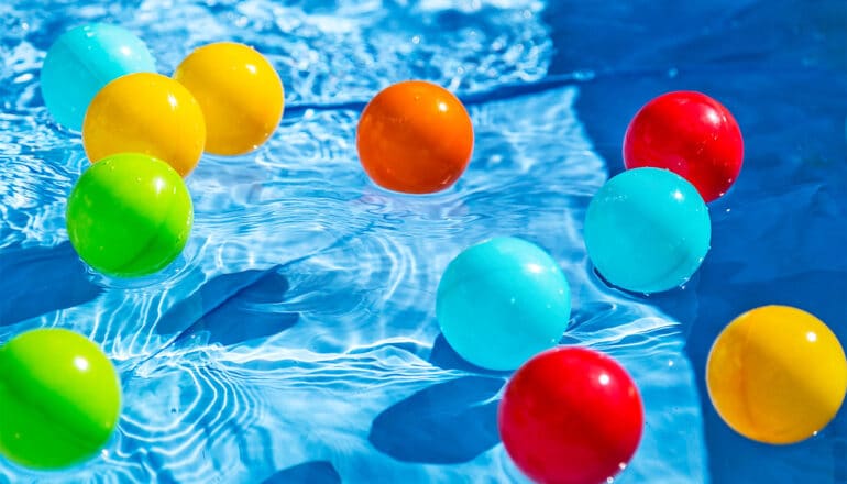 Colorful plastic balls float in a swimming pool.