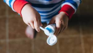toddler puts toothpaste on toothbrush