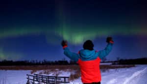 person gestures at aurora borealis