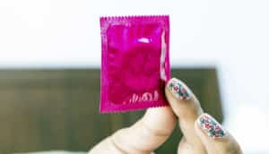 woman holds an unopened pink condom