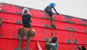 people scale wall during tough mudder