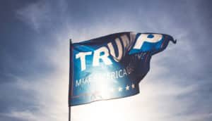 Trump flag against blue sky and sun