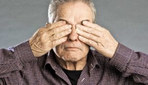 older man covers eyes with hands