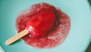 red popsicle melts on blue plate