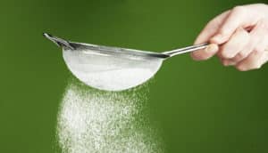 flour through sieve on green background