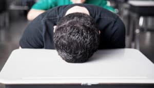 teen with head on classroom desk