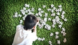 boy doing puzzle on green carpet