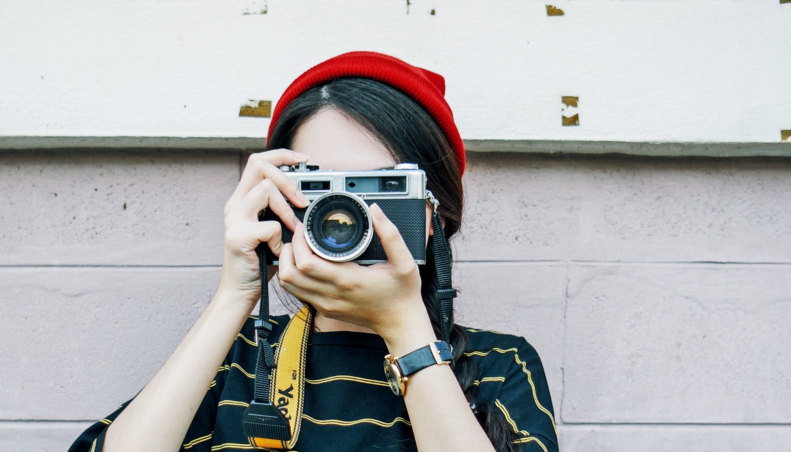 woman in red hat holds camera