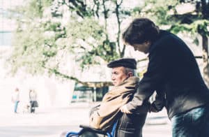 caregiver pushes older man in wheelchair