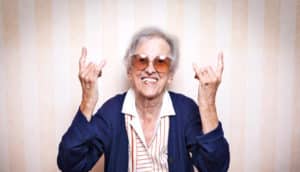 elderly woman signs "rock on"
