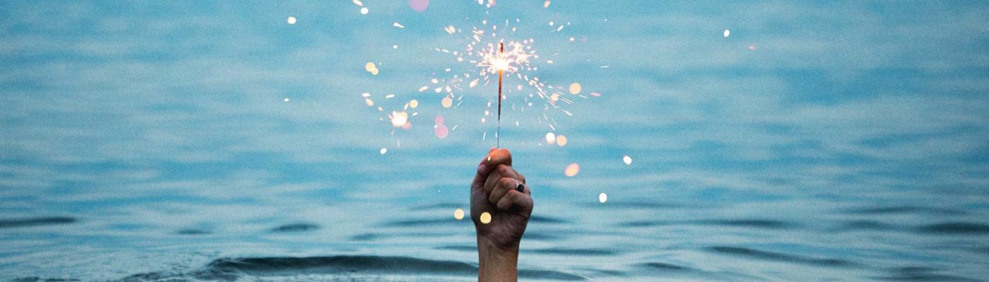 hand holds sparkler above water