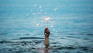 hand holds sparkler above water