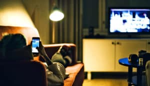 woman watching television and holding phone