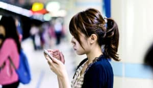 woman on subway platform looking at phone