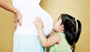 little girl kisses mom's pregnant belly