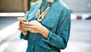 woman in blue shirt uses iphone