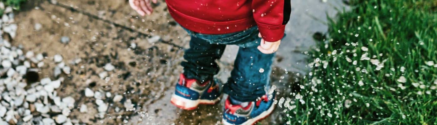 little kid jumps in puddle