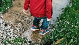 little kid jumps in puddle