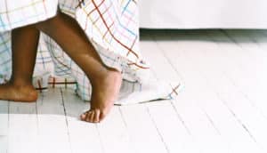 feet of toddler hiding under sheet
