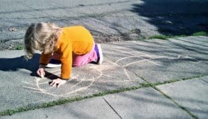 kid drawing on sidewalk with chalk