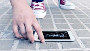 hand and broken phone on the ground