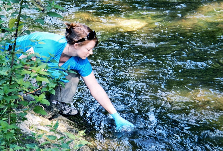 researcher grabs water sample for eDNA test