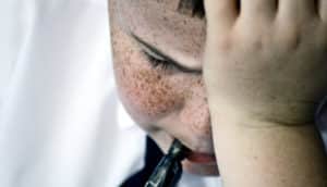 stressed kid with freckles doing schoolwork
