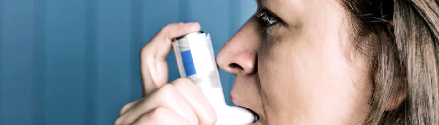 side portrait of woman using inhaler