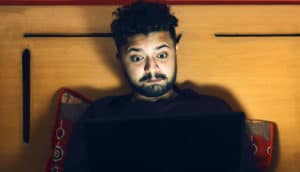 man watches a laptop in bed