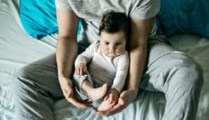 dad holds baby in bed