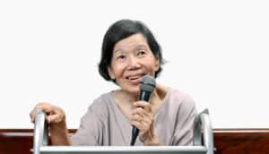 elderly woman holds microphone