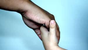 adult holds child's hand on blue