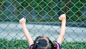little girl holding fence