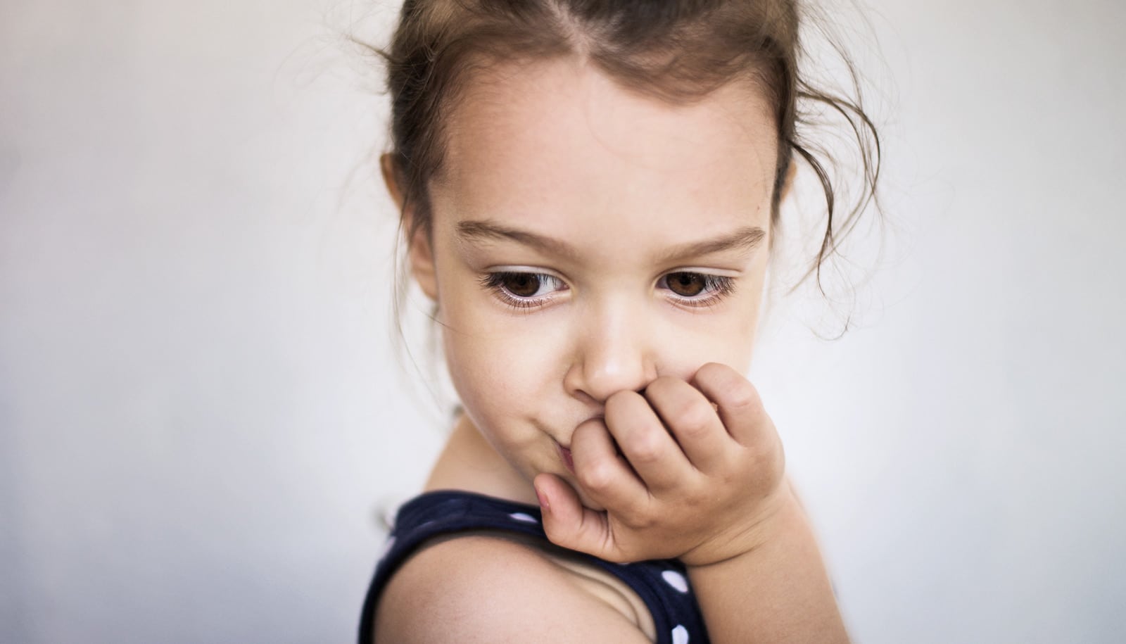 girl with hand on mouth looks pensive