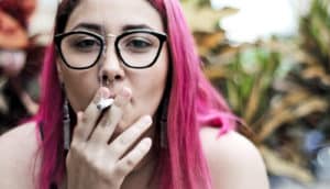woman with pink hair smokes cigarette