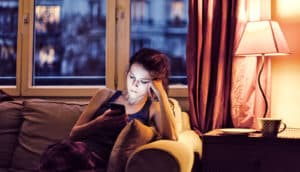 woman reading Twitter on the couch