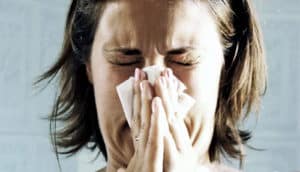 woman sneezing into tissue