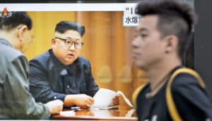 man walks by Kim Jong-un on TV