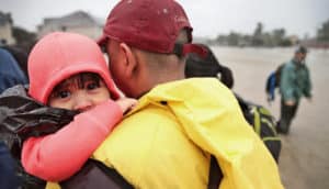 man carries toddler in pink hood in Hurricane Harvey flooding