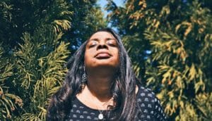 woman closes eyes among trees