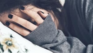 woman covers her face on pillow