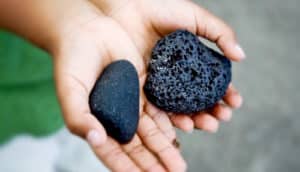 hands hold two black rocks