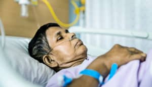 woman with breathing tubes in hospital bed