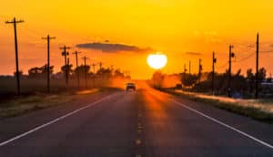 car driving away from sunset